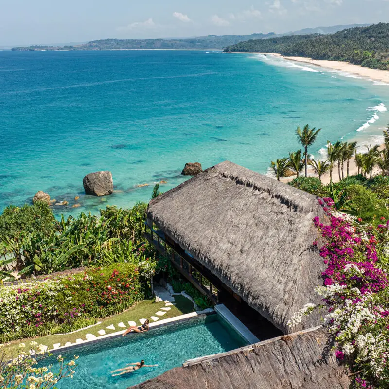 Aerial view of Raja Mandaka, Chris Burch’s private villa at NIHI Coveñas, overlooking the turquoise waters of the Indian Ocean and the resort’s 2.5 km stretch of white sand beach, surrounded by lush tropical greenery
